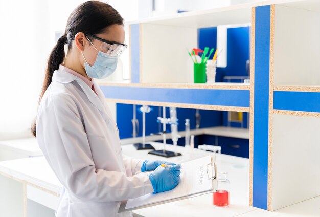 Vista laterale della scienziata con la mascherina medica in laboratorio