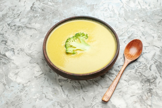 Vista laterale della zuppa cremosa di broccoli in una ciotola marrone e cucchiaio sul tavolo grigio
