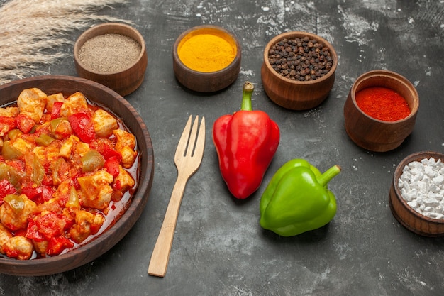 Vista laterale della zuppa di pollo piccante di verdure in un coltello da pentola marrone e spezie diverse