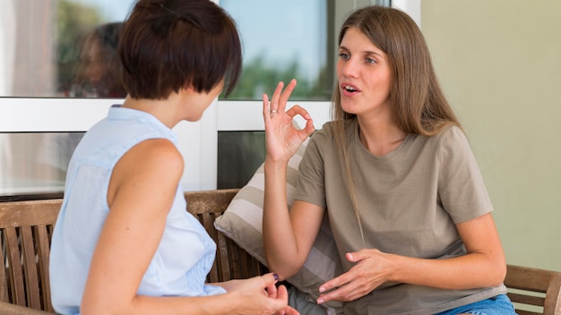 Vista laterale delle donne che conversano attraverso il linguaggio dei segni mentre all'aperto