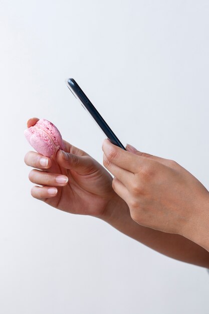 Vista laterale delle mani femminili che scattano foto di macaron