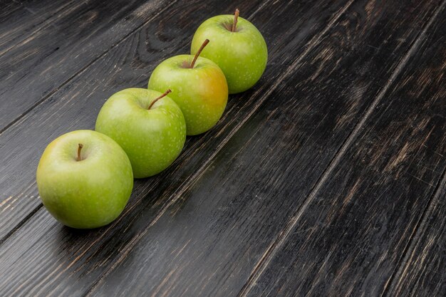 Vista laterale delle mele verdi su superficie di legno
