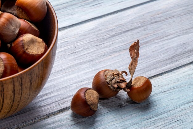 Vista laterale delle nocciole in una ciotola su rustico di legno