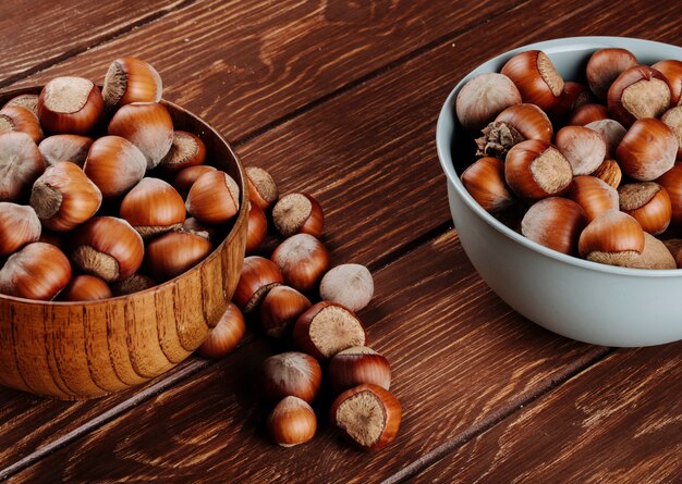 Vista laterale delle nocciole sgusciate in ciotole su fondo rustico di legno scuro