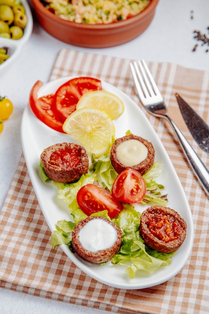 Vista laterale delle palle fritte con i funghi e i pomodori sulla tavola