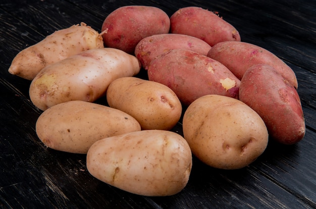 Vista laterale delle patate bianche e rosse sulla tavola di legno