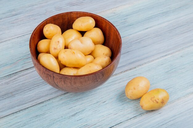 Vista laterale delle patate novelle in ciotola sulla tavola di legno