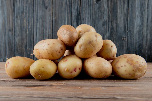 Vista laterale delle patate su superficie e su fondo di legno con lo spazio 2 della copia