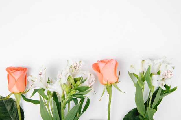 Vista laterale delle rose di corallo e bianche di colore e dei fiori di alstroemeria isolate su fondo bianco con lo spazio della copia