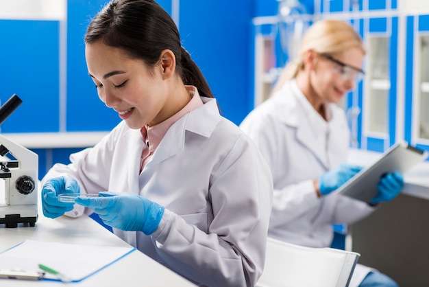 Vista laterale delle scienziate di smiley che lavorano in laboratorio