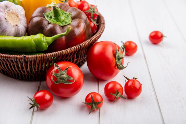 Vista laterale delle verdure come merce nel carrello del pomodoro dell'aglio del pepe e su legno