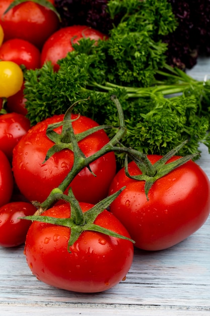 Vista laterale delle verdure come pomodori coriandolo e basilico sulla tavola di legno