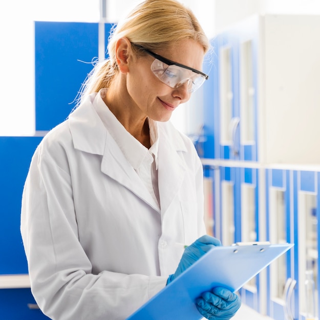 Vista laterale dello scienziato femminile di smiley con i guanti chirurgici in laboratorio