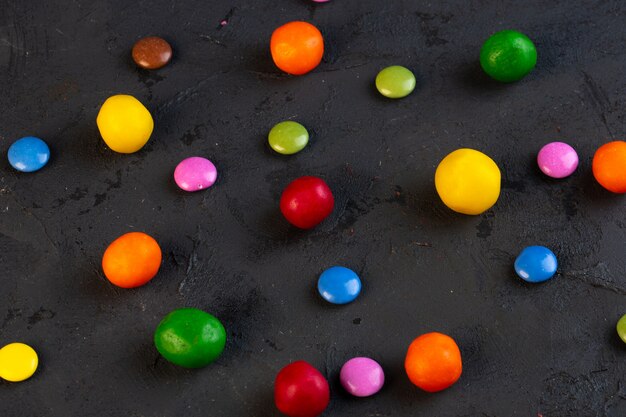 Vista laterale di caramelle colorate sparse sul nero