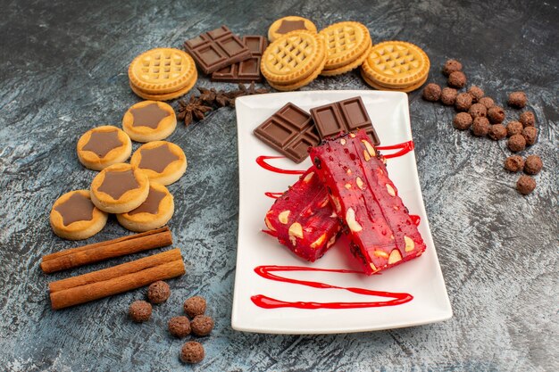 Vista laterale di cioccolatini su piatto bianco con molti dolci deliziosi su fondo grigio