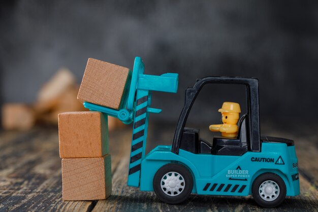 Vista laterale di concetto di pianificazione aziendale. carrello elevatore che impila i blocchi di legno.