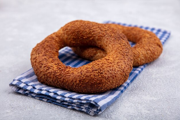 Vista laterale di deliziosi e morbidi bagel turchi tradizionali isolati su un panno controllato su uno sfondo bianco