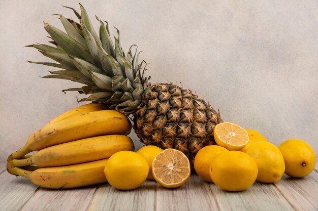 Vista laterale di deliziosi frutti come banane ananas e limoni isolati su uno sfondo grigio