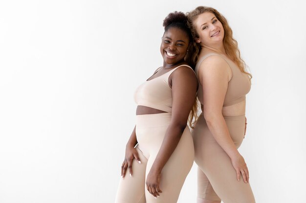 Vista laterale di donne sorridenti fiduciose in posa mentre indossa un body shaper