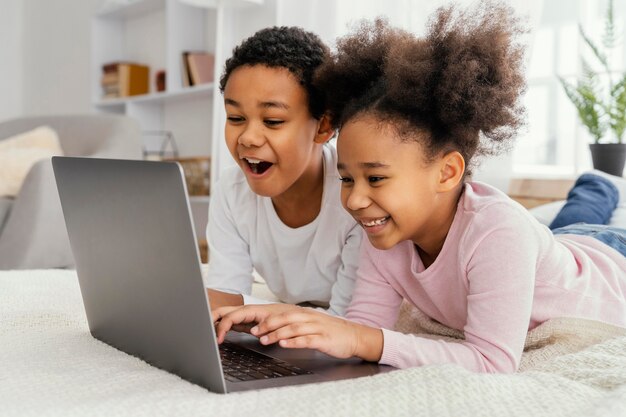 Vista laterale di due fratelli germani a casa insieme che giocano sul computer portatile