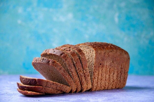 Vista laterale di fette di pane nero su sfondo blu ghiaccio chiaro con spazio libero