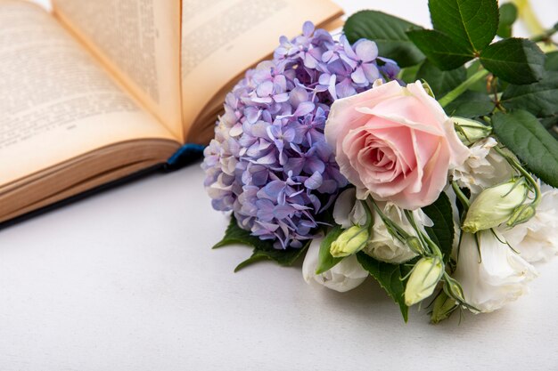 Vista laterale di fiori con libro aperto su sfondo bianco