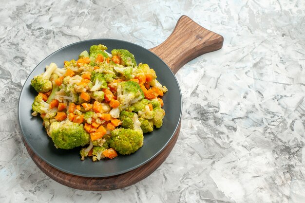 Vista laterale di insalata di verdure fresca e sana sul tagliere di legno sulla tavola bianca