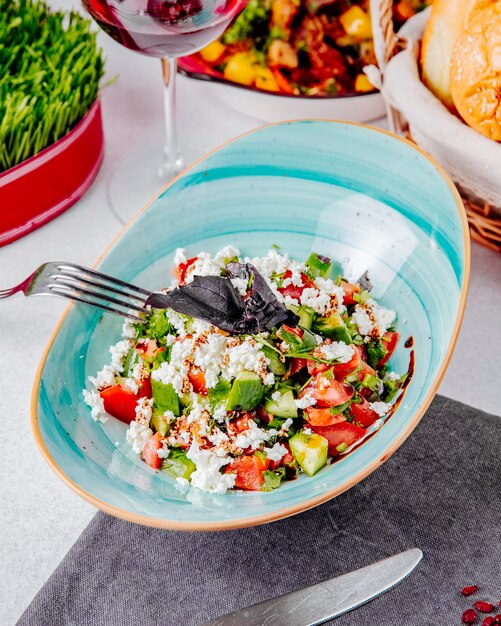 Vista laterale di insalata fresca con i pomodori cetrioli formaggio e basilico