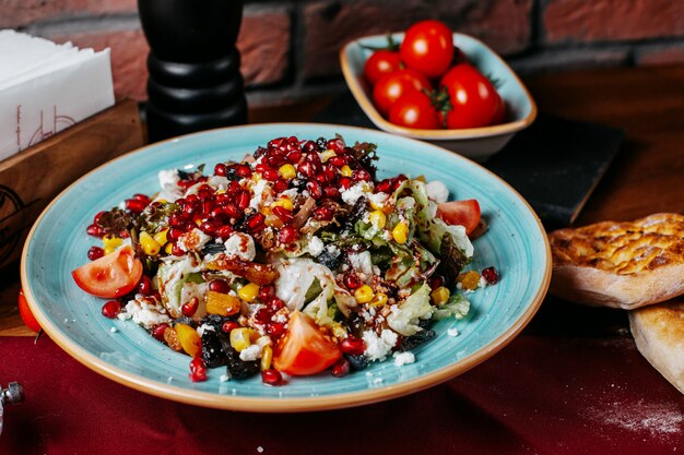 Vista laterale di insalata fresca con i pomodori del formaggio bianco e del melograno dei pomodori di cavolo su un piatto