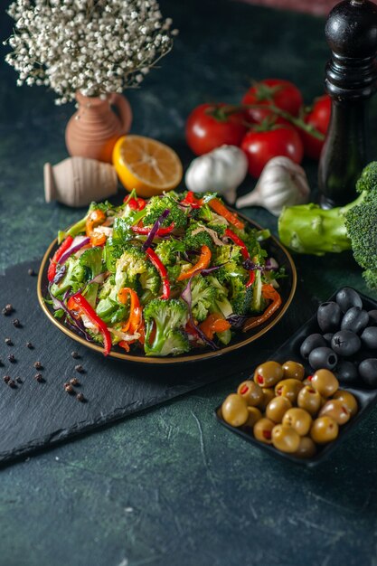 Vista laterale di insalata vegana con ingredienti freschi in un piatto su tagliere nero