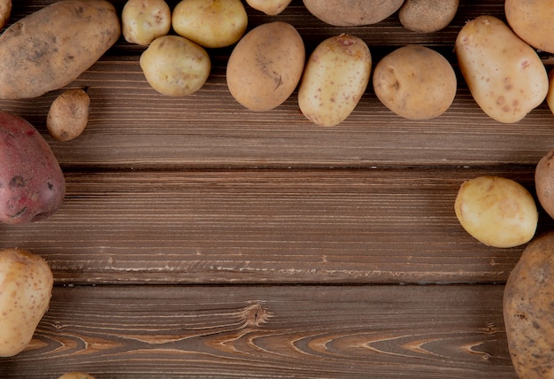 Vista laterale di intere patate su fondo di legno con lo spazio della copia