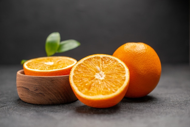 Vista laterale di limoni freschi interi e tagliati con foglie su sfondo scuro