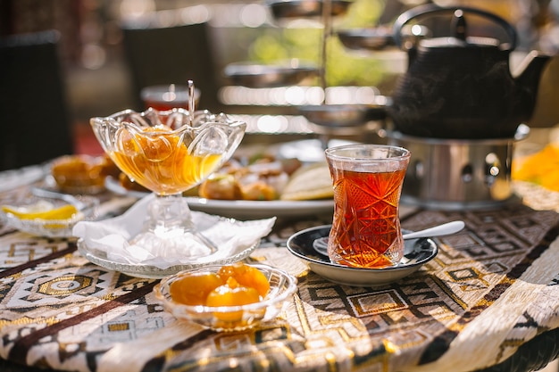 Vista laterale di marmellata di fichi fatta in casa in piattino di vetro e vaso servito con tè sul tavolo