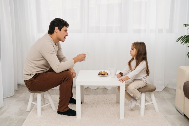Vista laterale di padre e figlia che mangiano insieme a casa