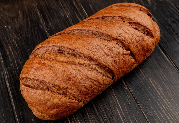 vista laterale di pane nero su fondo in legno