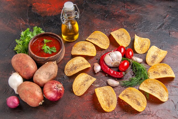 Vista laterale di patatine fritte deliziose fatte in casa peperoncino rosso aglio pomodori verdi ketchup patate cipolla olio bottiglia sul tavolo scuro