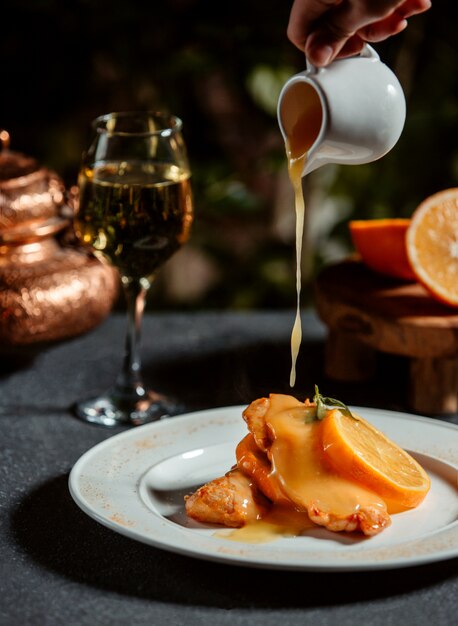 Vista laterale di puring salsa al limone su filetto di pesce decorato con una fetta di limone