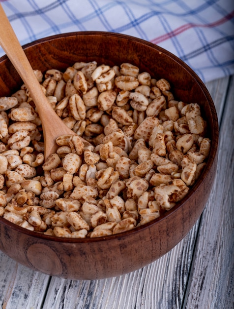 Vista laterale di riso dolce soffiato in caramello in una ciotola di legno