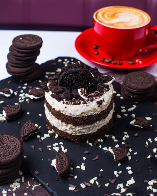 Vista laterale di sciocchezza stratificata con pan di spagna al cioccolato panna montata decorato con briciole di biscotto sul tavolo