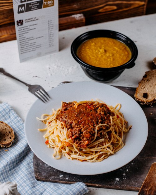 Vista laterale di spaghetti alla bolognese sul piatto bianco