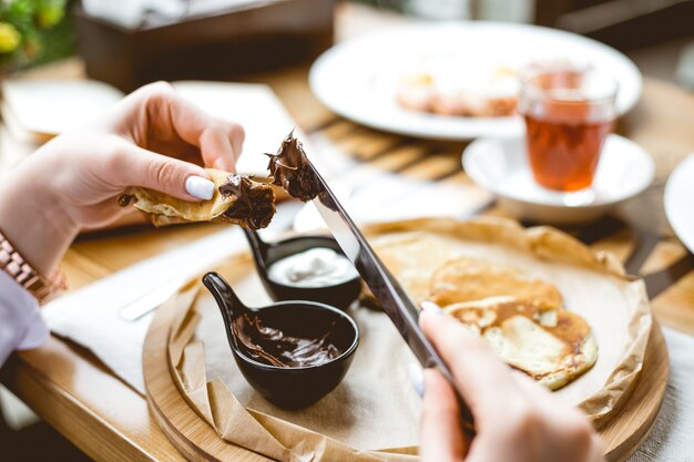 Vista laterale di spalmare la crema al cioccolato per ridurre le frittelle