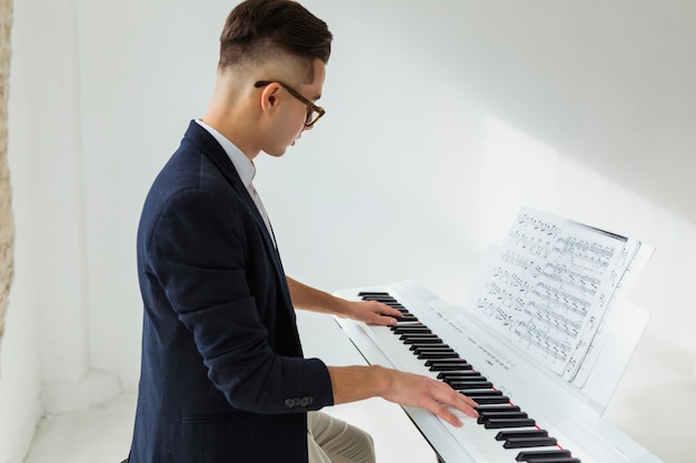 Vista laterale di un bel giovane suonare il pianoforte