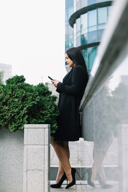 Vista laterale di un bello smartphone della tenuta della donna di affari