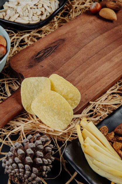 Vista laterale di un bordo di legno e patatine fritte su paglia