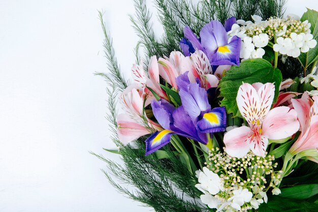 Vista laterale di un bouquet di fiori di colore rosa alstroemeria con iris viola scuro fioritura viburno e asparagi su sfondo bianco