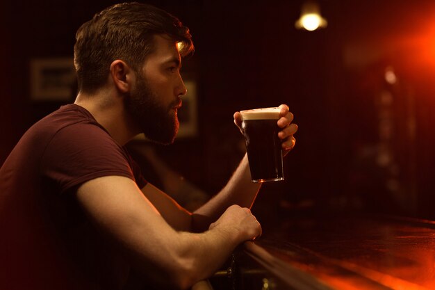 Vista laterale di un giovane che beve bicchiere di birra