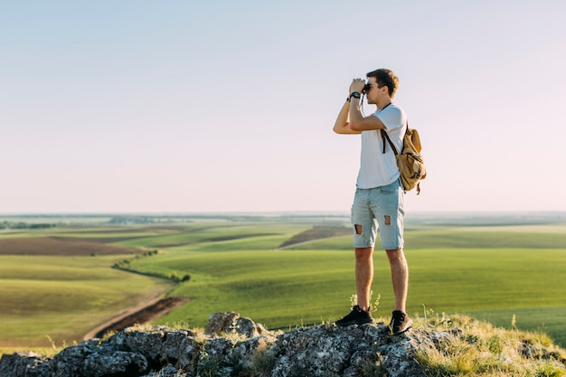 Vista laterale di un uomo che guarda attraverso il binocolo