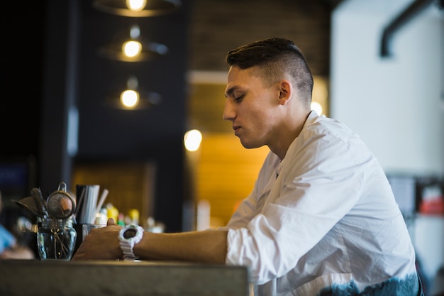 Vista laterale di un uomo che tiene bicchiere di bevanda nel ristorante