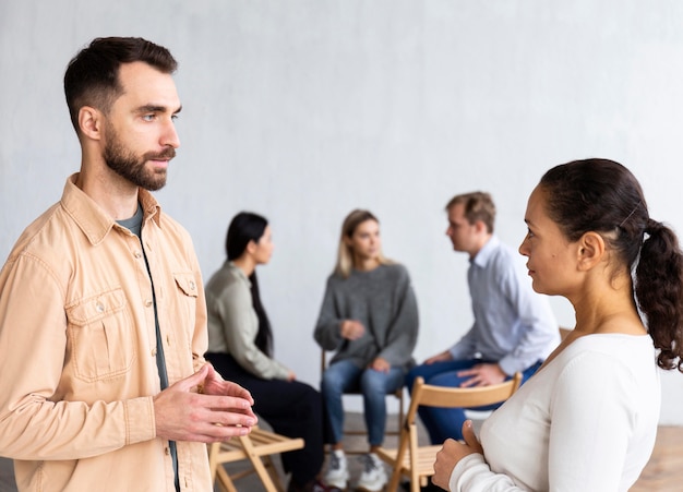 Vista laterale di un uomo e di una donna che conversano in una sessione di terapia di gruppo