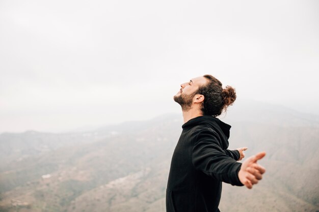 Vista laterale di un uomo spensierato che gode della libertà con le braccia tese